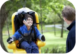 Child with a disability playing on swing, smiling at his parent.